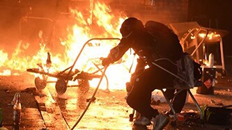 A shadowed man crouches near fire