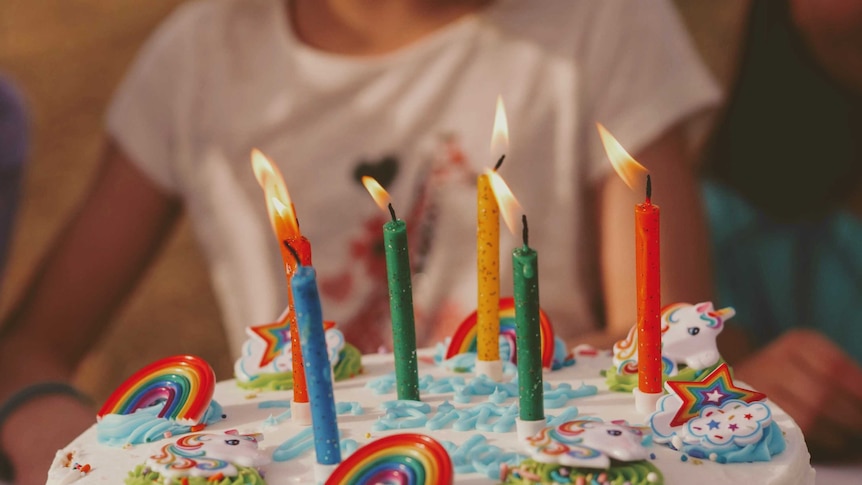 A child's brightly decorated birthday cake with lit candles