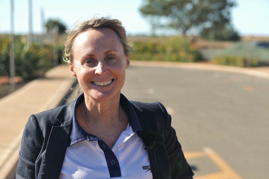 Woman wearing white polo shirt and blue blazer in the sun.