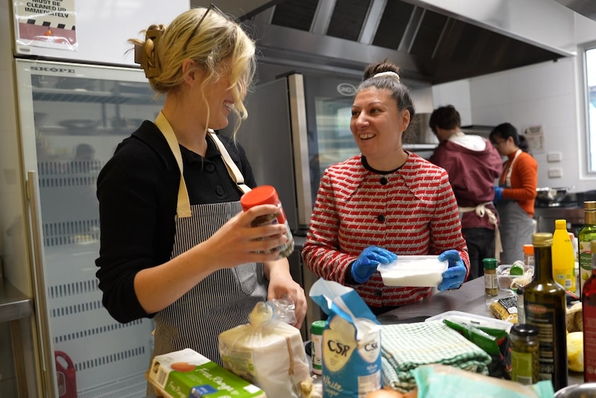 Two women smiling at each other in a kitchen