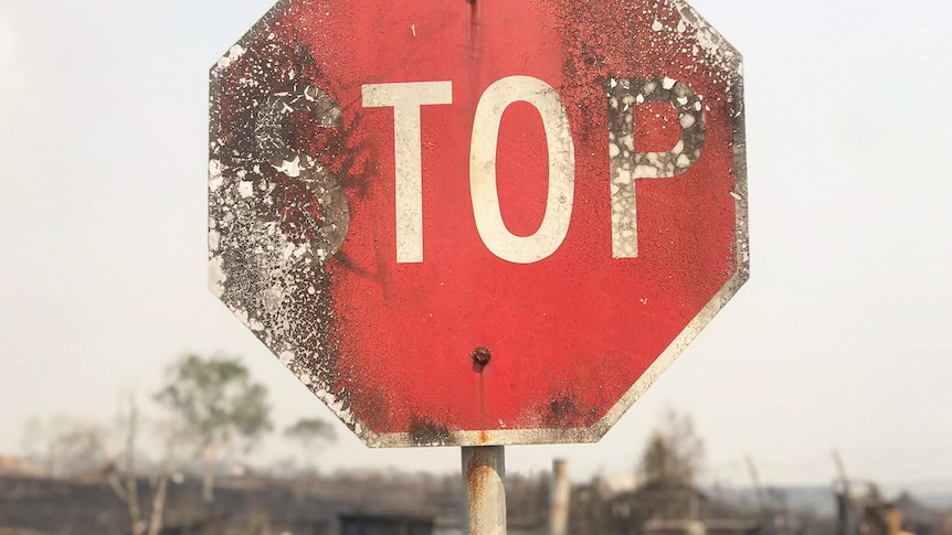 Close-up of burnt stop sign on road in bushfire-ravaged area at Sarina in north Queensland.