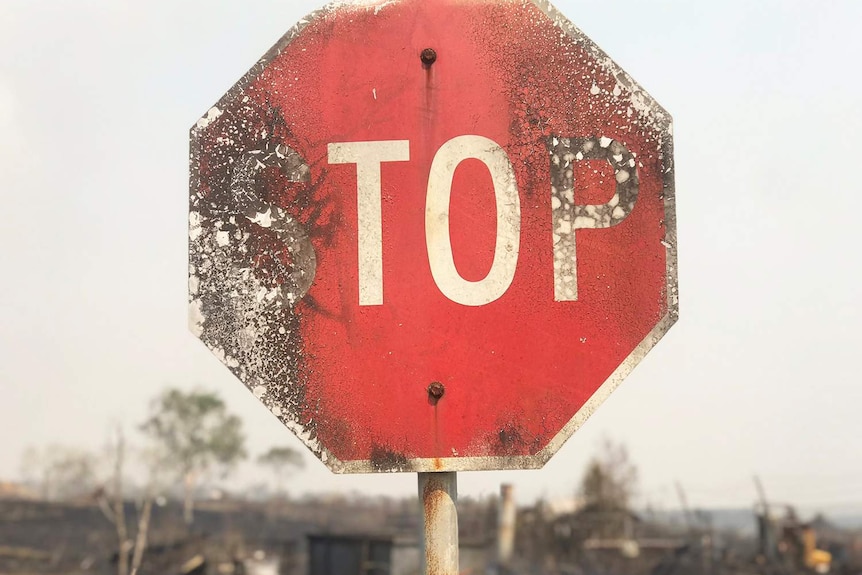 Close-up of burnt stop sign on road in bushfire-ravaged area at Sarina in north Queensland.