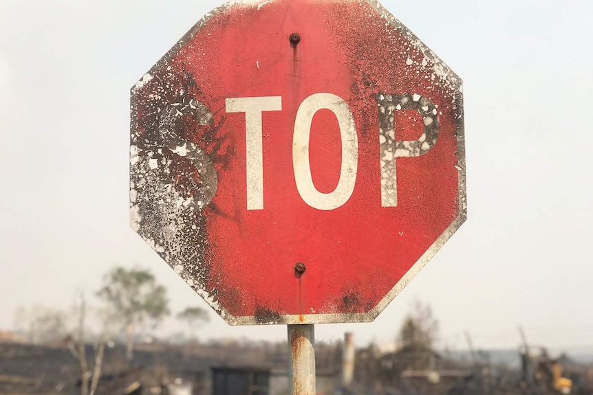 Close-up of burnt stop sign on road in bushfire-ravaged area at Sarina Beach in north Queensland.