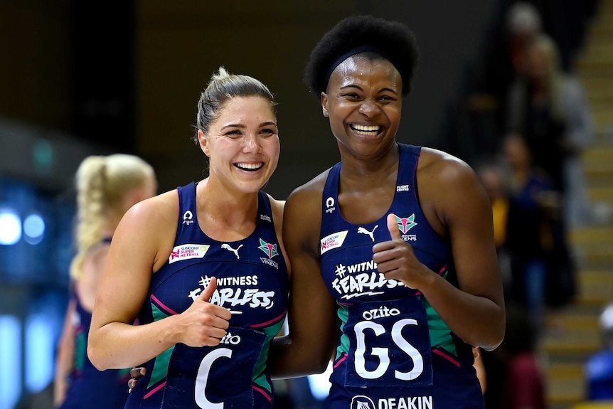Two Melbourne Vixens Super Netball players smile as they celebrate beating the Giants.