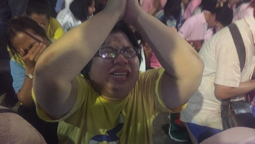 A crowd in Thailand cry after hearing the announcement that their King is dead.