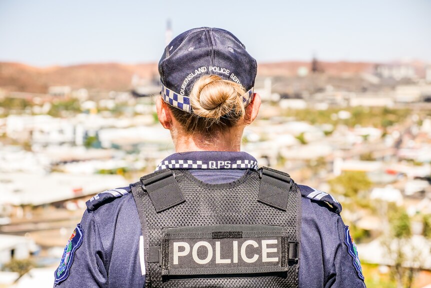 A mid-shot of the back of a female police officer with the town of Mount Isa sprawling out in front of her.