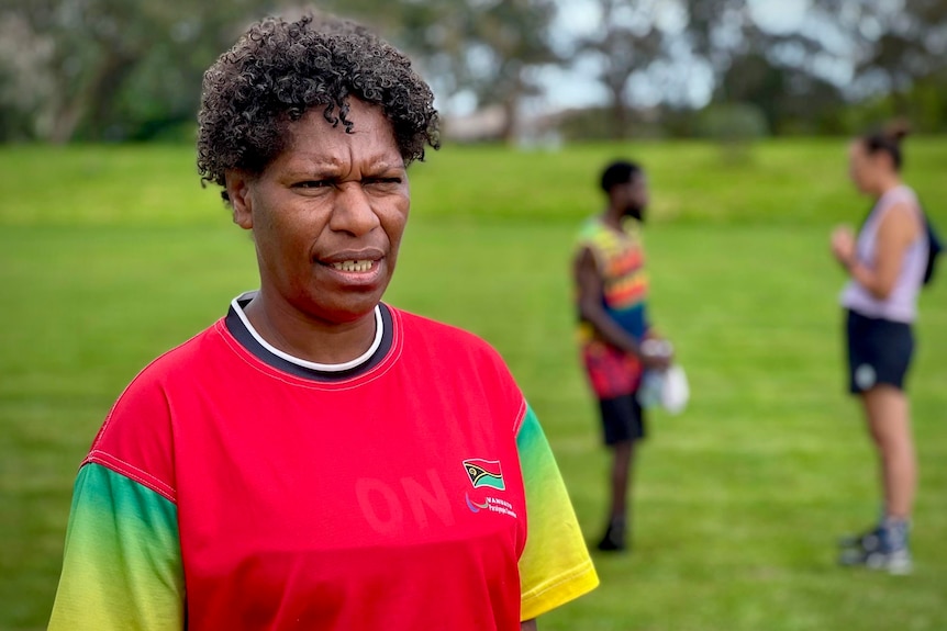 A Pacific Islander woman coaching outdoors.