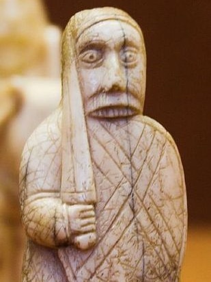 A walrus ivory chess set depicting a shield-chewing berserker.