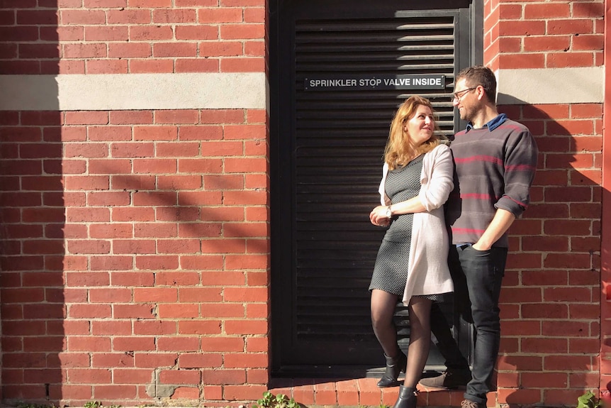 Shahad Bannan (left) standing in a doorway looking at her husband Rasan Haddad (right).