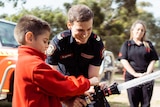 A close-up shot of firefighter Michael Hatfield holding a fire hose with a student from Mosman Park School for Deaf Children.