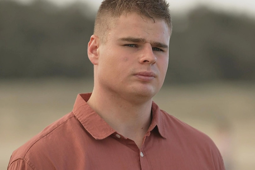 A young man wearing a red collared shirt.