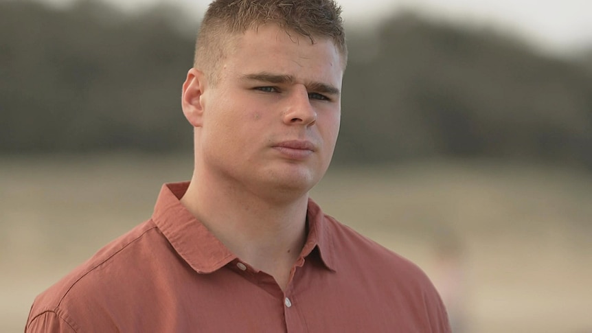 A young man wearing a red collared shirt.