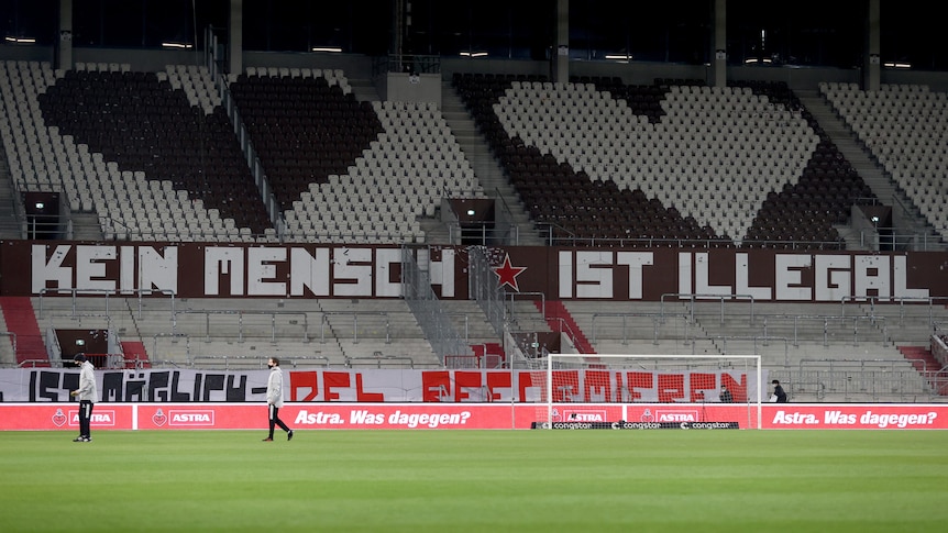 A soccer stadium has a banner with two love hearts and a pro-immigration message