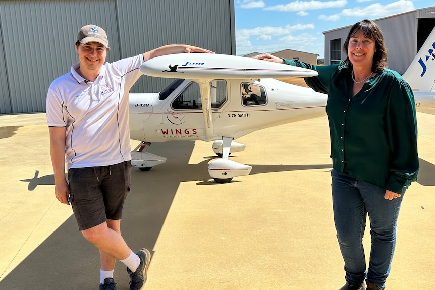 Man and woman stand beside light plane