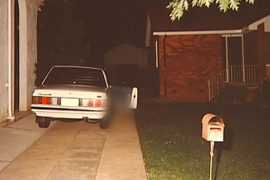 A white car parked in a driveway with the door open. The image is partially blurred to hide Mr Winchester's body.