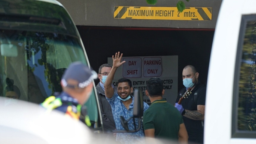 A refugee waves as he walks to a bus from the Park Hotel Melbourne.