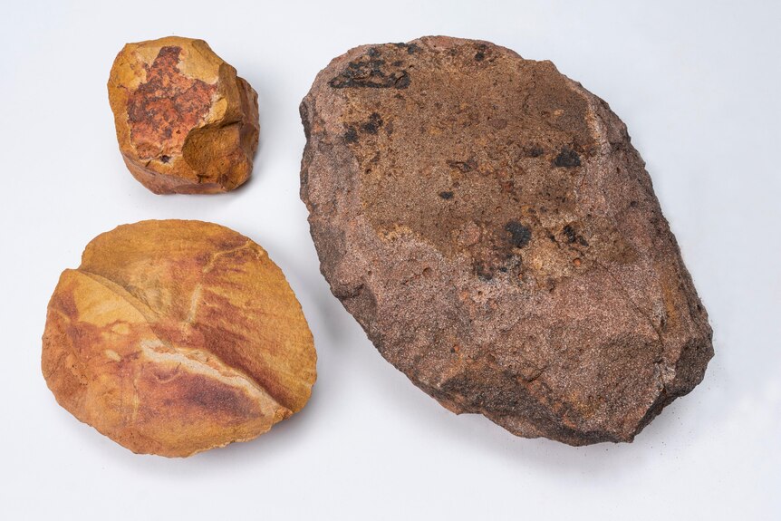 A close-up of three stones of different sizes, coloured brown to orange.