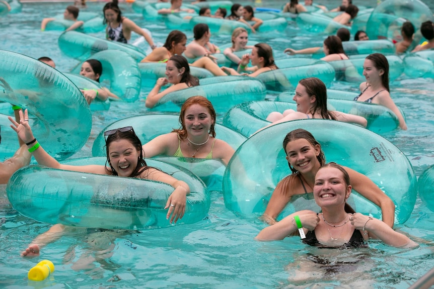 Young girls playing on inflatable rings in a pool.