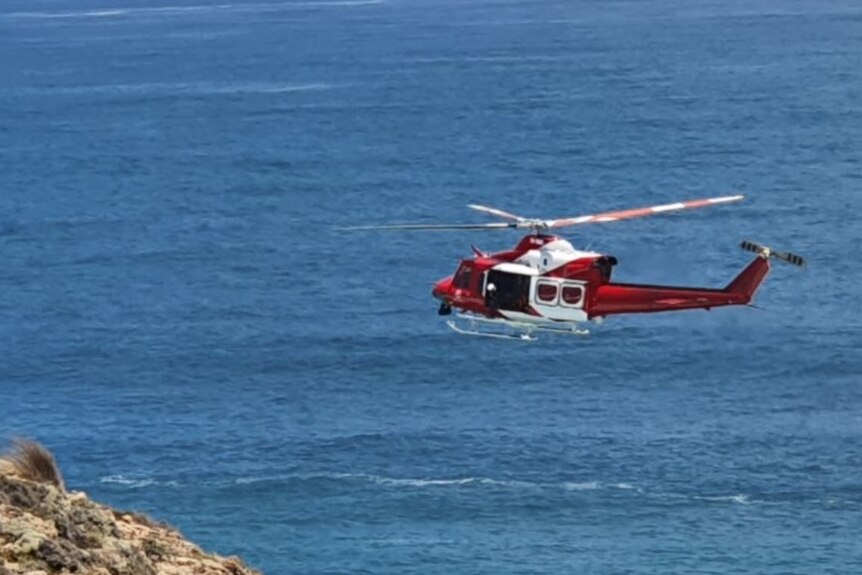 A helicopter over the sea and a cliff
