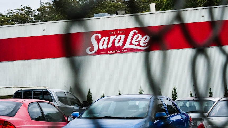 A fence in front of a white wall with Sara Lee written on a red background.