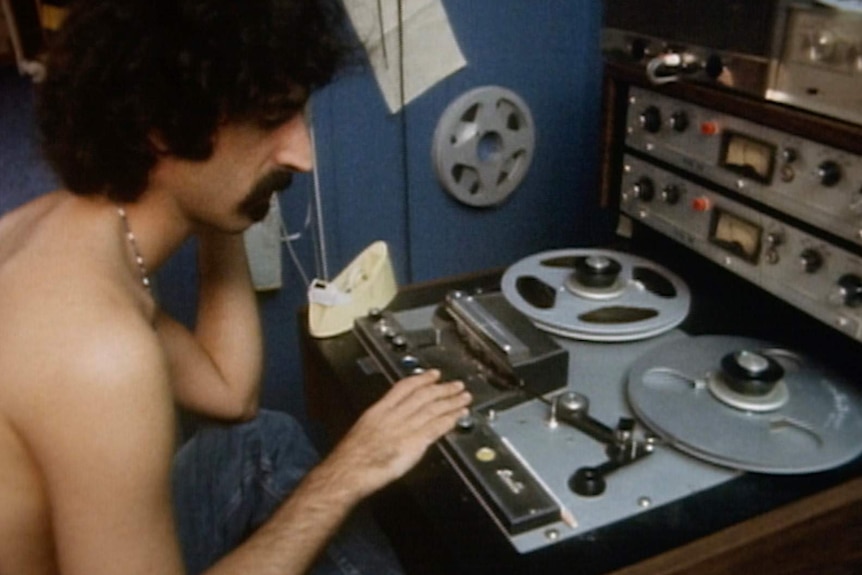 Frank Zappa sitting by recording equipment.