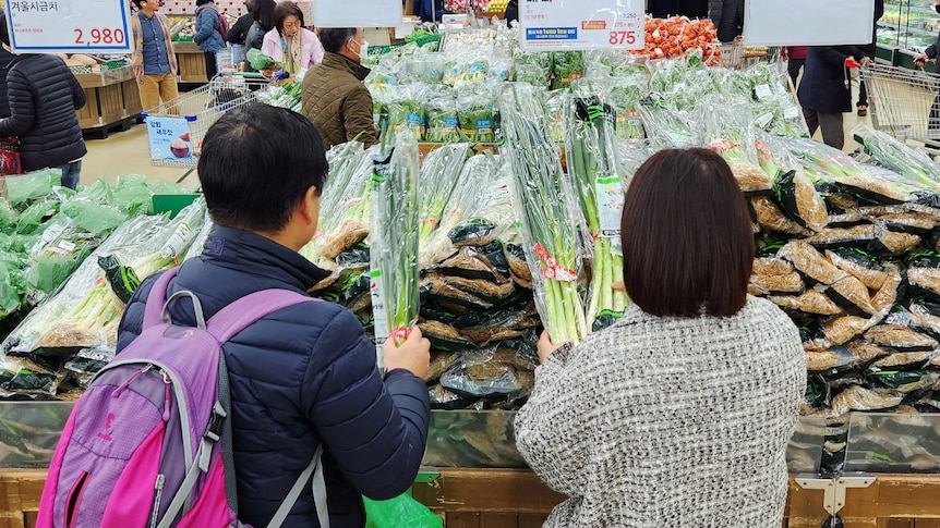 Women shop for green onions at a market in Seoul.