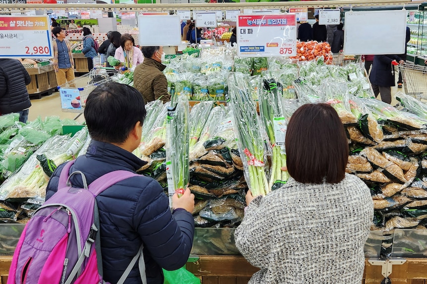 Women shop for green onions at a market in Seoul.