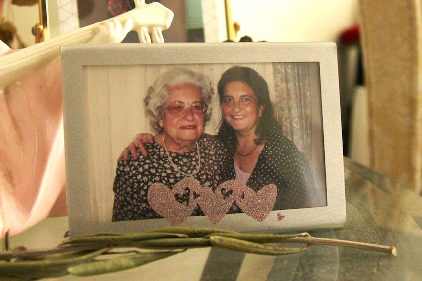 An older woman and younger woman smile in a picture frame portrait.