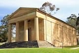 A sandstone building with columns in a Australian bush setting