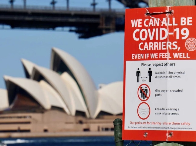 A COVID-19 information sign with the Sydney Opera House pictured in the background.