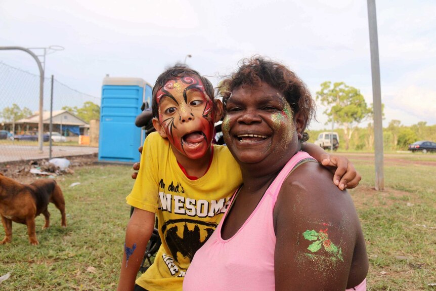 A woman smiles for the camera with her arm around her young nephew, who is pulling a funny face.