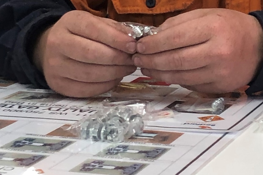 Close up of hands holding some bolts in a small plastic bag.