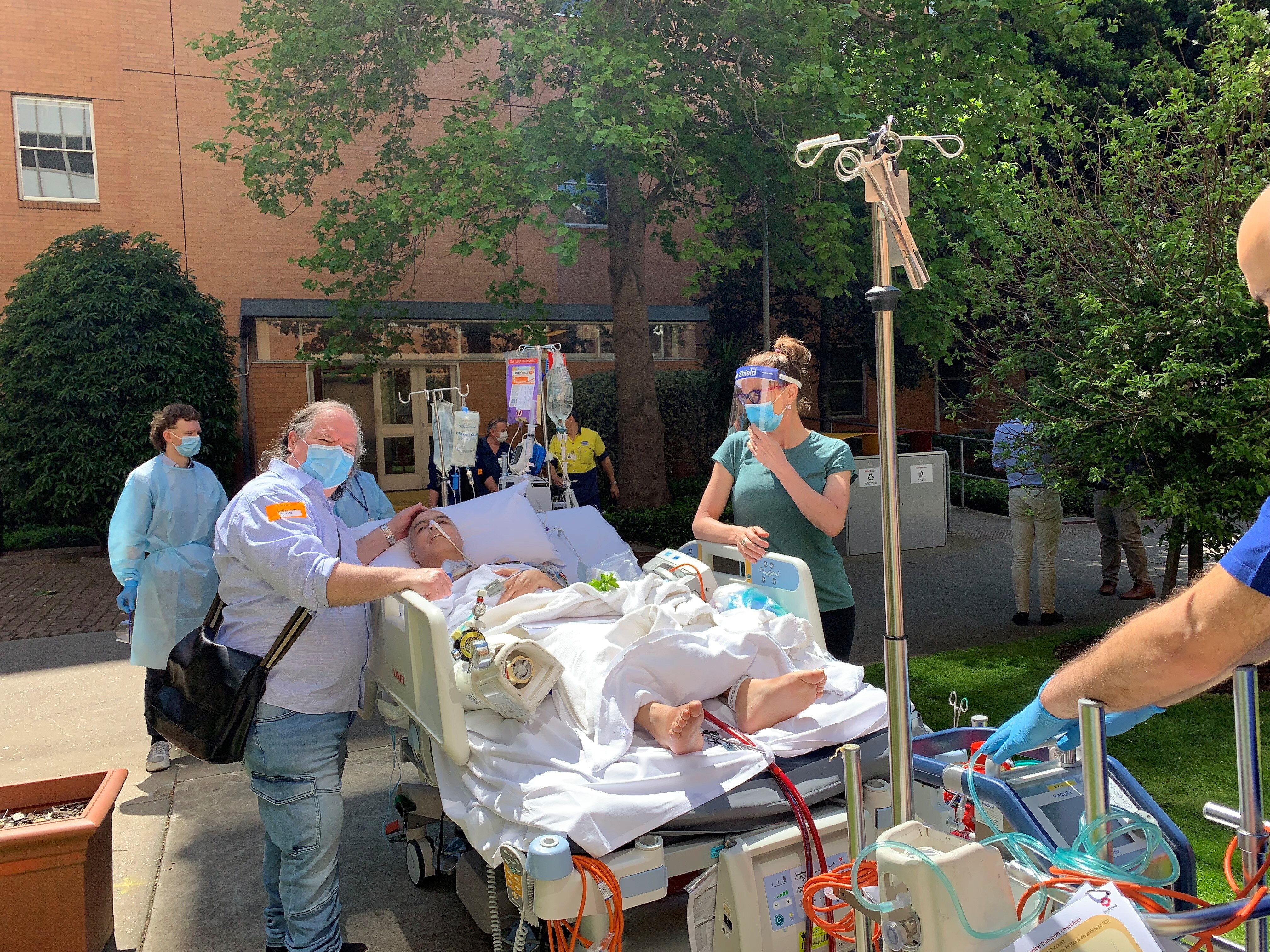 A man in a hospital bed surrounded by medical staff.