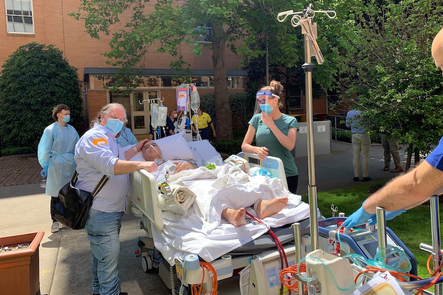 A man in a hospital bed surrounded by medical staff.