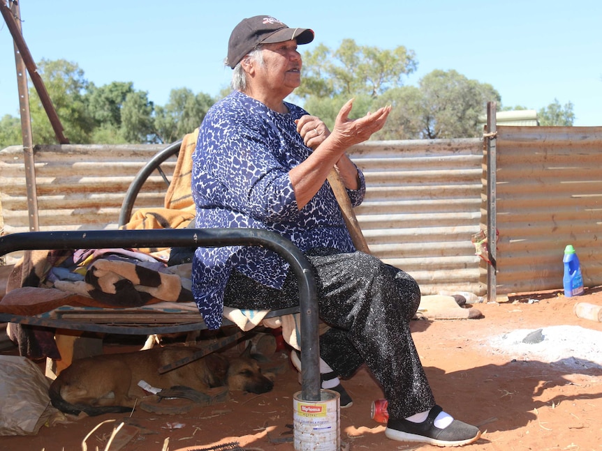 Rosalie Kunoth-Monks sits on a bed in the open air at Utopia