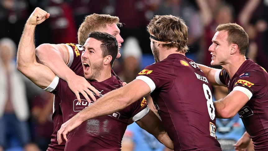 Ben Hunt screams with his fist clenched as he is hugged by his teammates