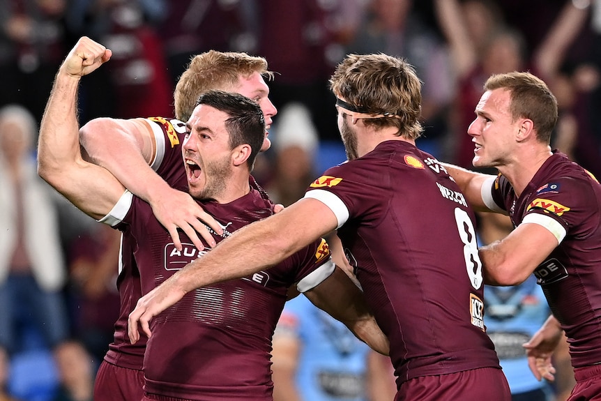Ben Hunt screams with his fist clenched as he is hugged by his teammates
