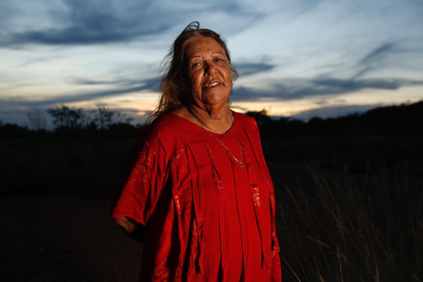 Linda looks at the camera in a portrait taken outside just after sunset.