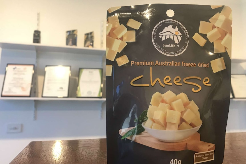 A packet of freeze dried cheese with food certificates on the shelf in the background.