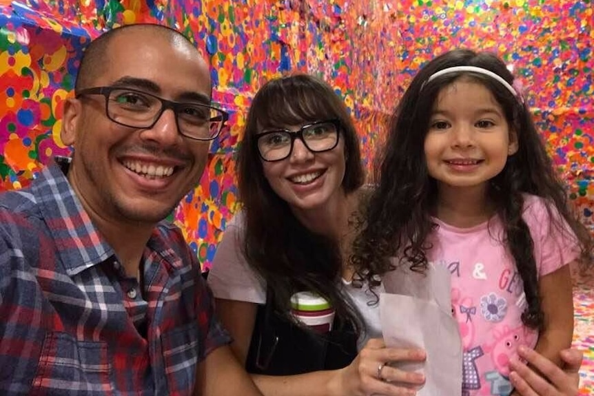 Elizabeth Pickworth smiles into the camera with her husband and young daughter.