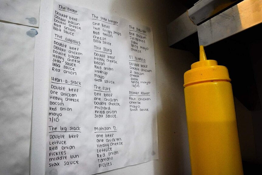 A mustard bottle sits next to a piece of paper on the wall listing instructions for the shop's special off-menu burger options.