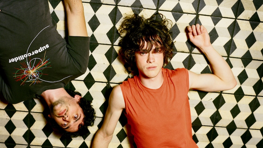 MGMT's Ben Goldwasser and Andrew VanWyngarden lie on a black and white tiled floor