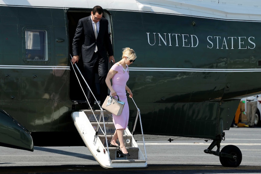 Steve Mnuchin and his wife Louise Linton step off US government plane.