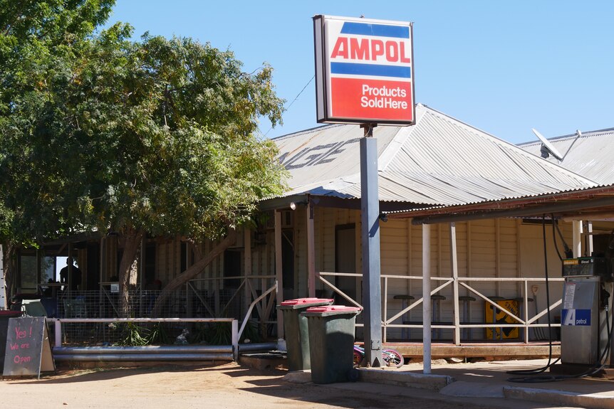 an old building with big verandas and a service station sign