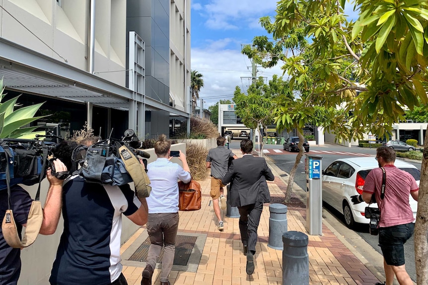 A man running away from journalists and cameramen