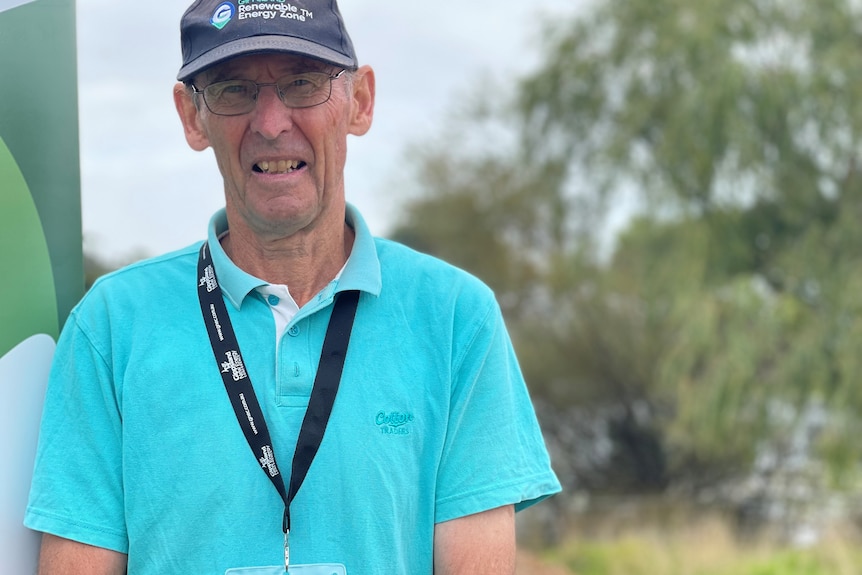 A man in an aqua t-shirt and cap