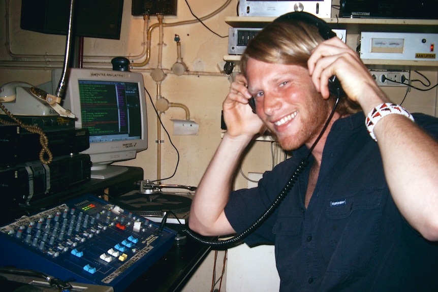 A young man sits in a mid-2000s pirate radio studio 