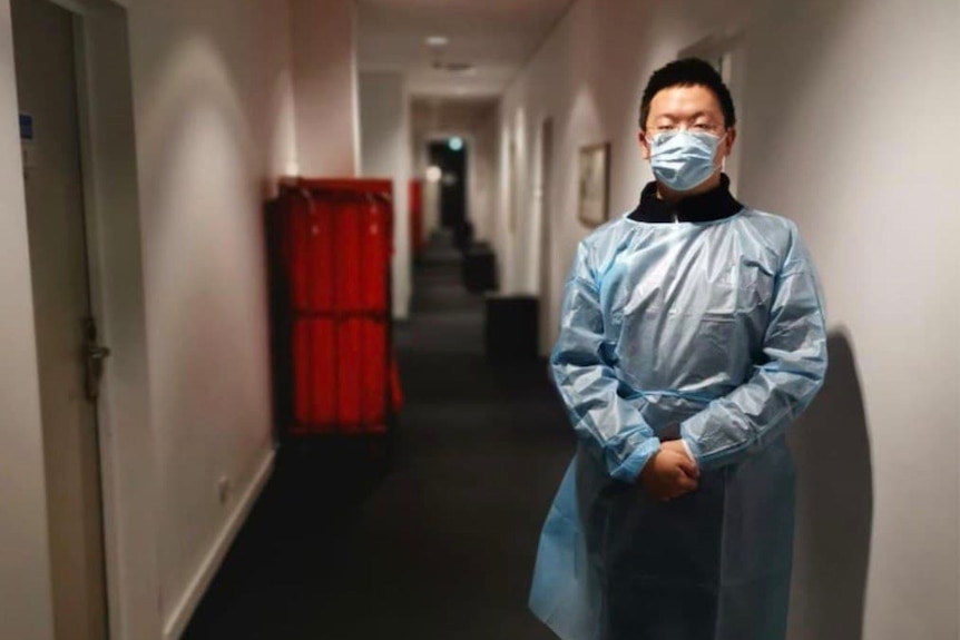 Two men work in a quarantine hotel wearing PPE. 