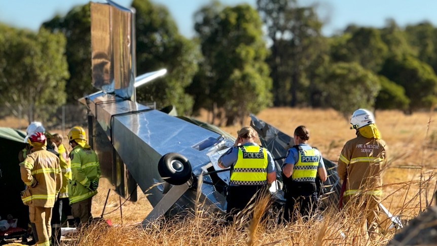 Police officers and firefighters inspect the wreckage of the plane that crashed near Bunbury on Friday