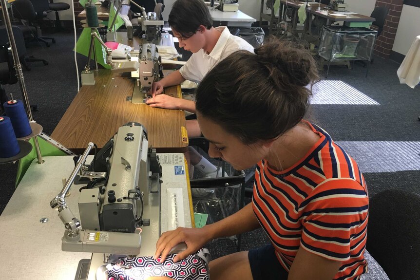 Fashion students Ruby Slockee (front) and Sean Ash-Williams sew sanitary items for girls in Cambodia.